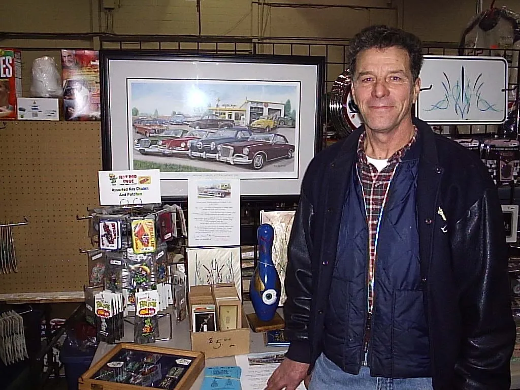 Ian Graham beside a print of Graham’s Garage which included many of his own personal Studebakers