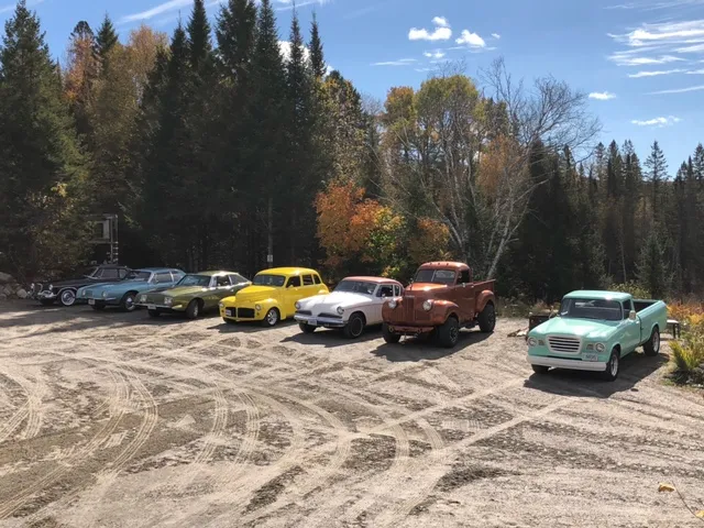 Members' Studebakers lined up on a gravel lot with fall colours behind